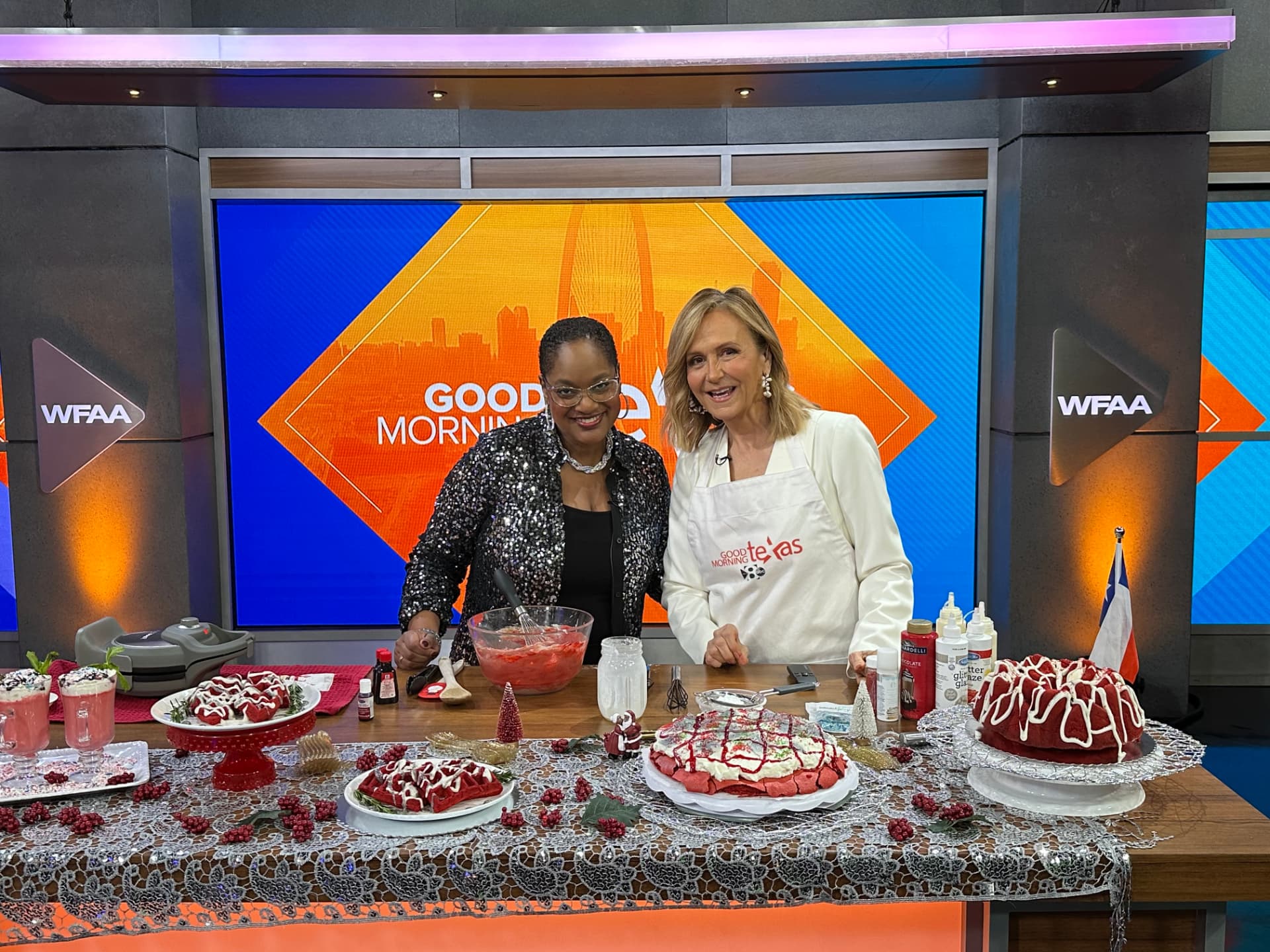 Chef Lorious with a red velvet dessert table — bundt cake, layer cake, waffles and milkshakes