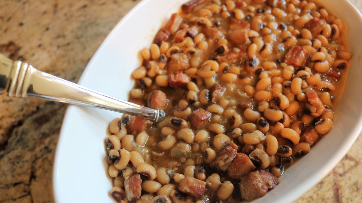 A white plate topped with beans and ham.