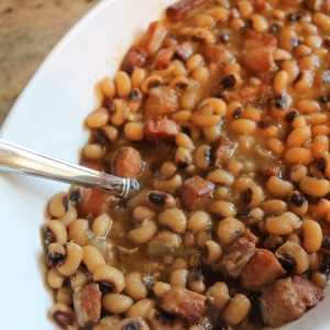 A white plate topped with beans and ham.