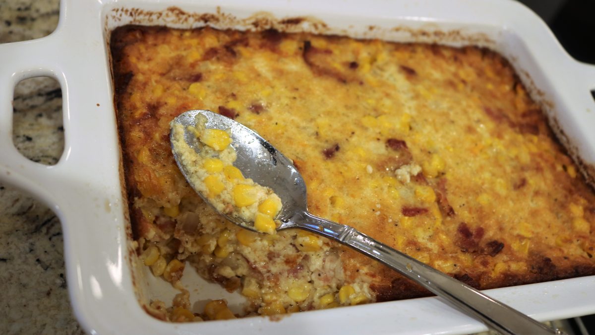 A spoon is in front of corn casserole with a spoon