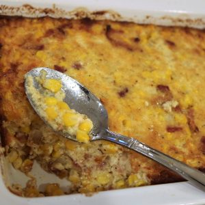 A spoon is in front of corn casserole with a spoon