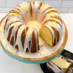 A bundt cake with white icing and lemon zest.