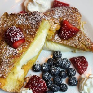 A plate of food with berries and whipped cream.