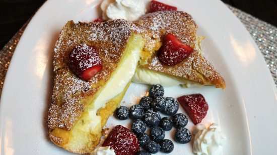 A plate of food with berries and whipped cream.