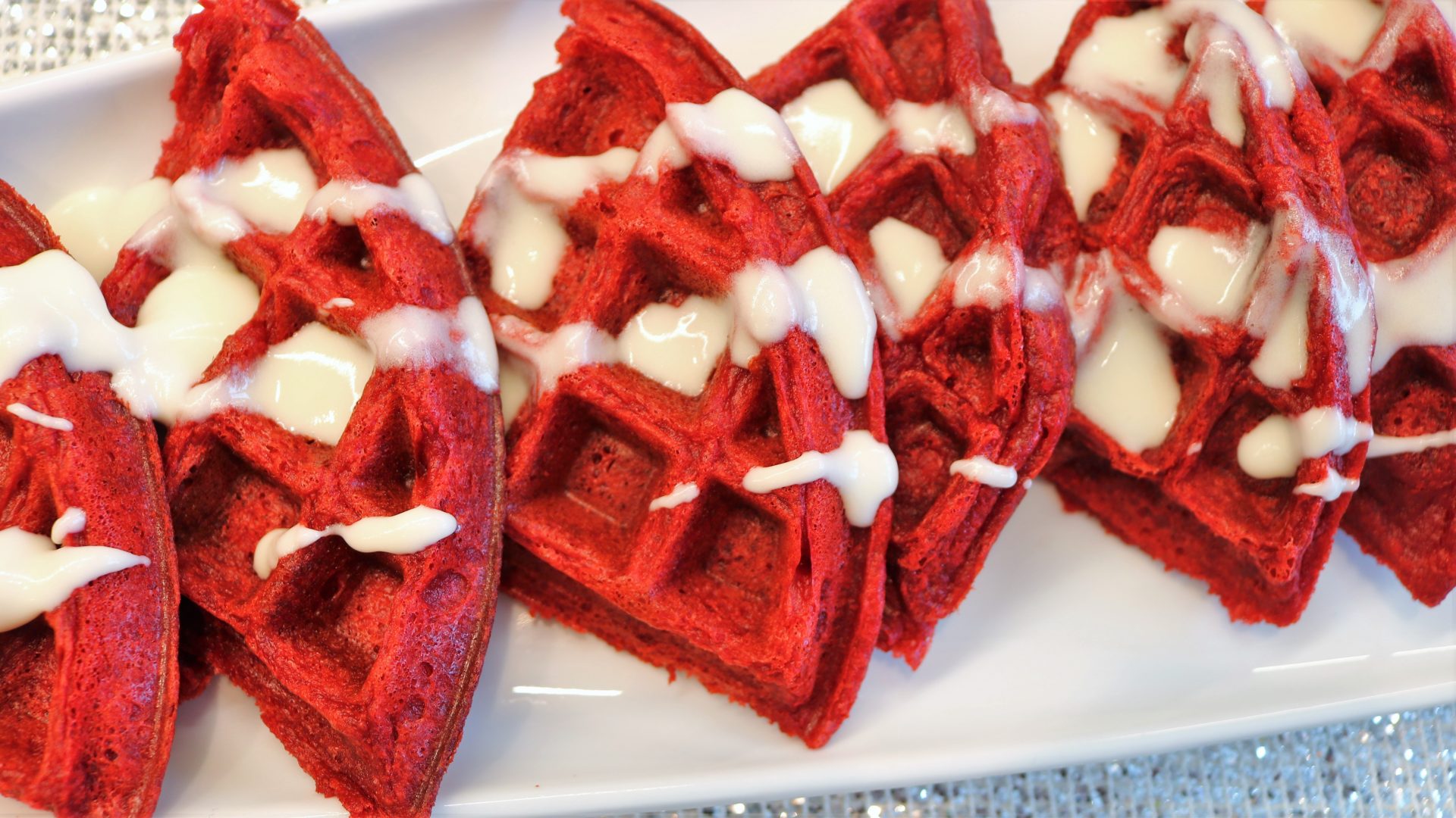 A plate of red velvet waffles with white frosting.