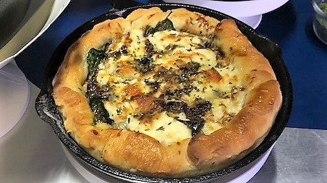 A pizza with cheese and spinach in it.
