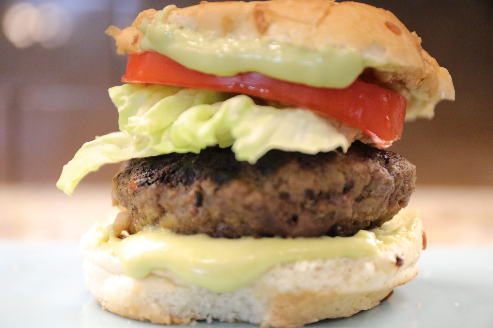 A hamburger with lettuce, tomato and mayonnaise on it.