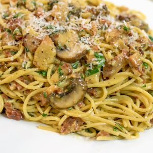A plate of pasta with mushrooms and meat.