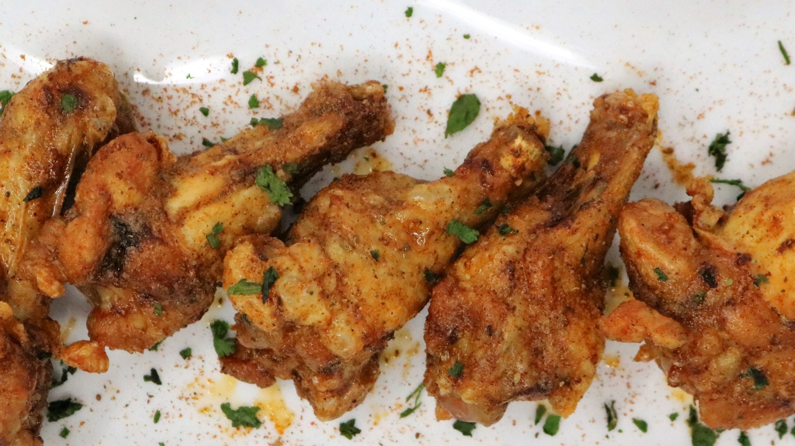 A plate of fried chicken with herbs on top.