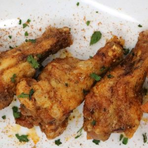 A plate of fried chicken with herbs on top.