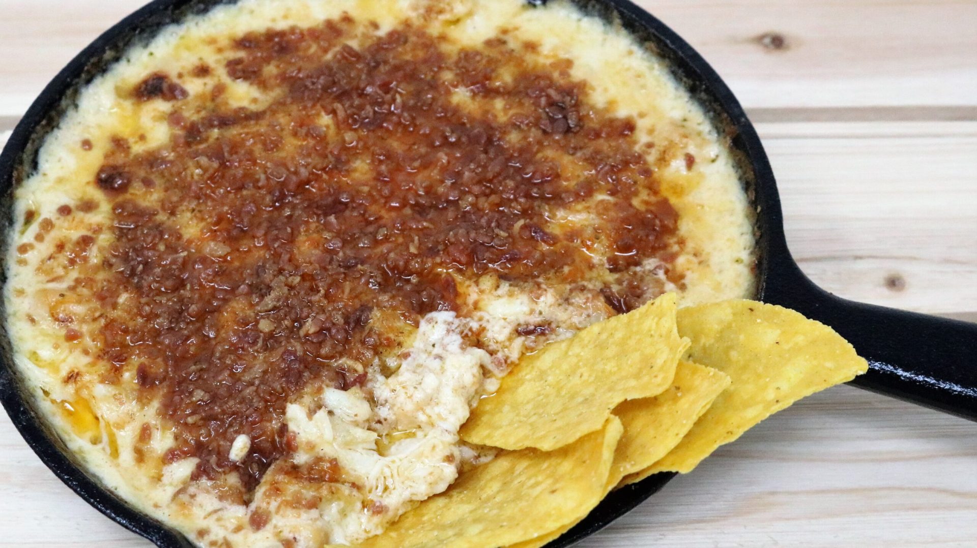 A bowl of dip with tortilla chips on the side.