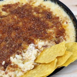 A bowl of dip with tortilla chips on the side.