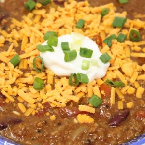 A bowl of chili with cheese and sour cream.