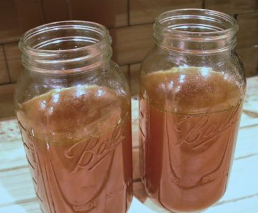 Two jars of juice sitting on a table.