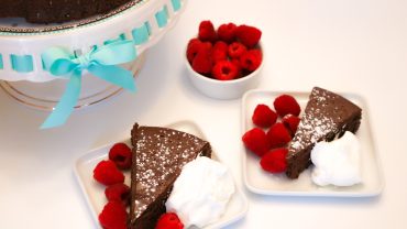 A slice of chocolate cake with raspberries on top.