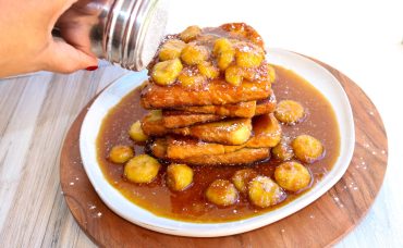 A plate of food with bananas and syrup on it.