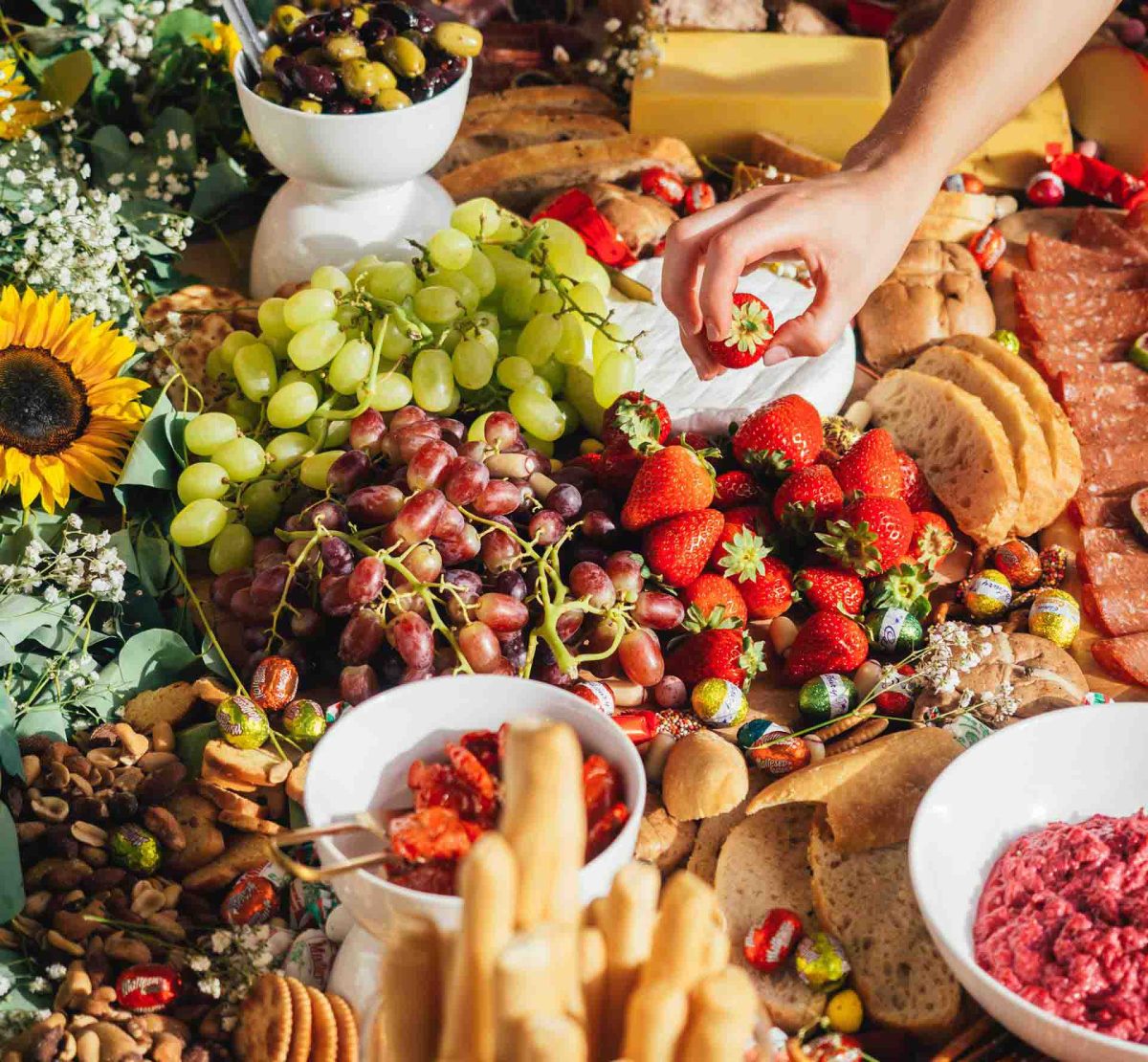 A table full of food with grapes, crackers and other snacks.