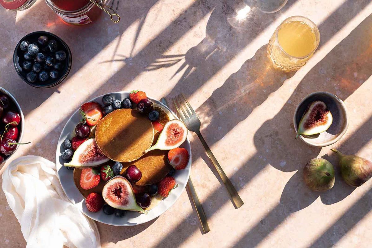 A plate of fruit and some drinks on the table.